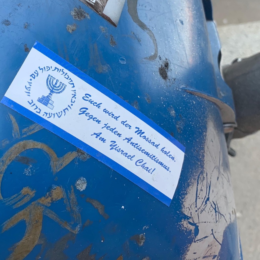 A horizontal sticker with a white background and blue stripes along the top and bottom.