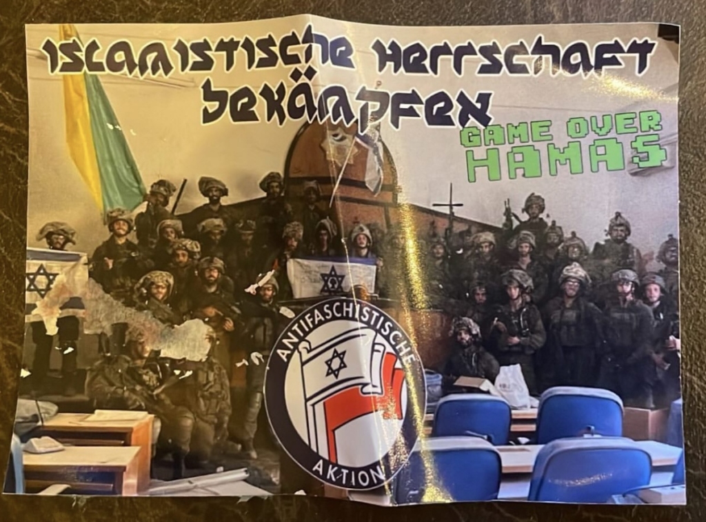 A photo of a group of Israeli soldiers in full combat gear posing in Gaza’s Palestinian Legislative Council building. Superimposed on this photo, text in a pseudo-Hebrew font, in black with a white outline, reads in German: “fight Islamic domination”. Next to it reads “game over Hamas”.